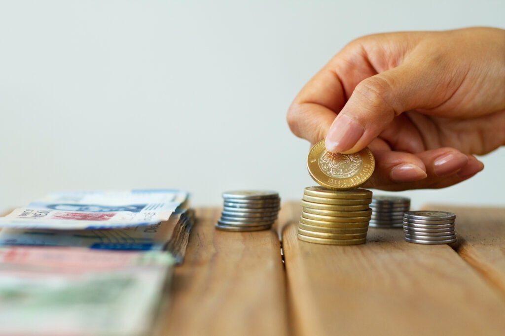Pilhar de dinheiro com moedas em cima de mesa.