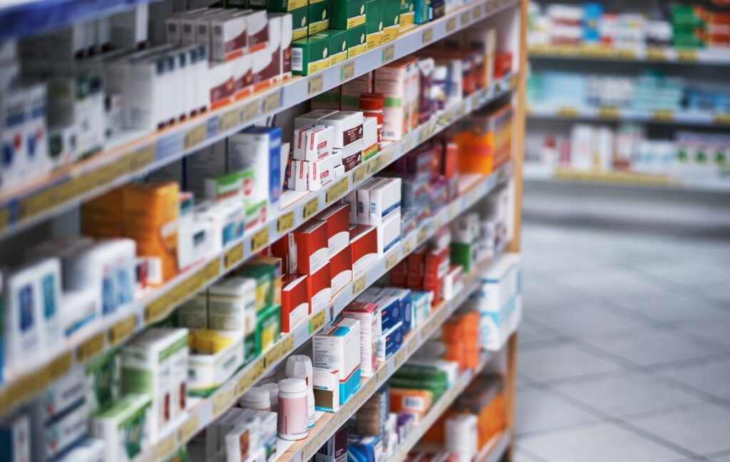 Foto de prateleiras repletas de vários produtos medicinais em uma farmácia.